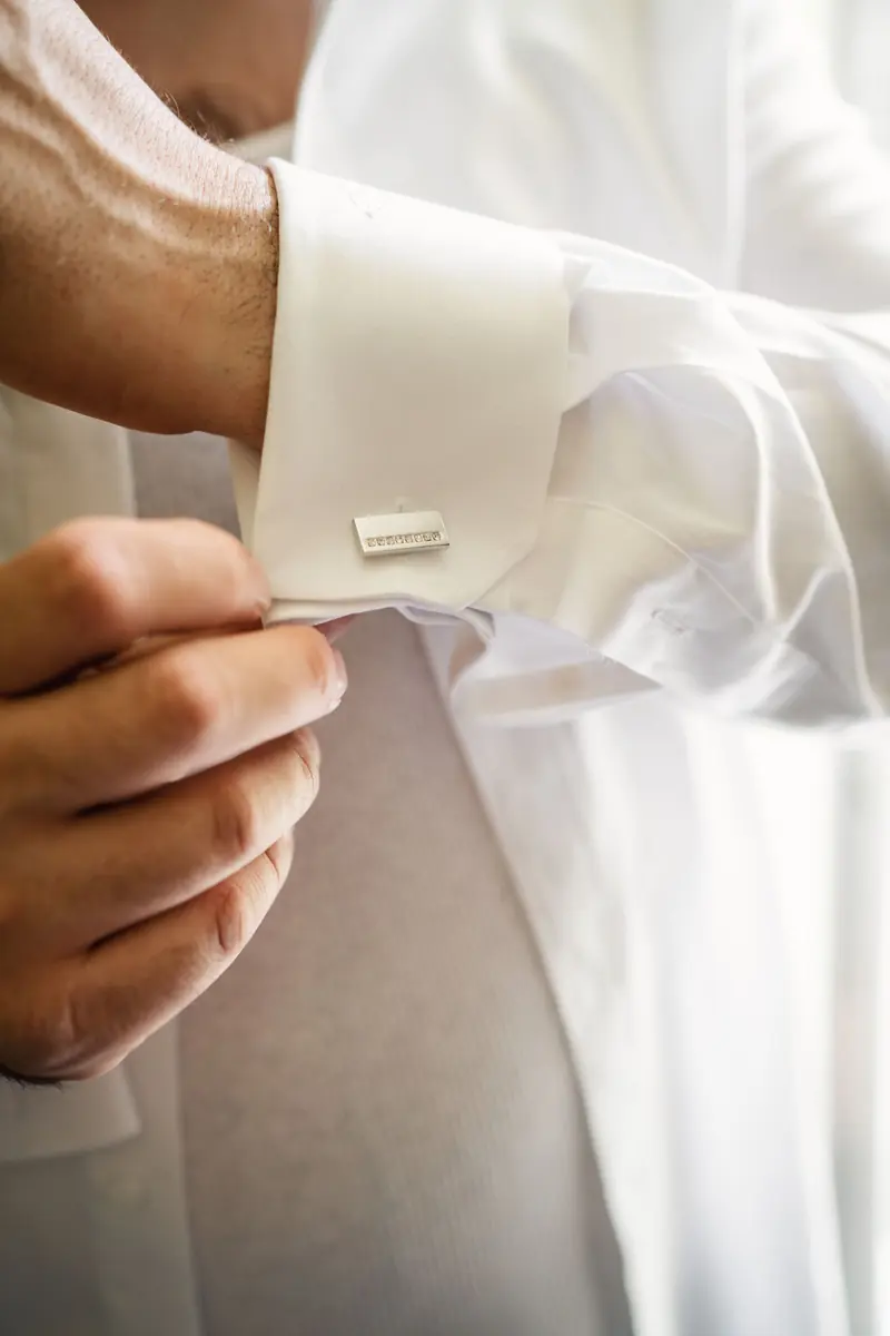 Groom fastening his shirt cuff on the wedding morning
