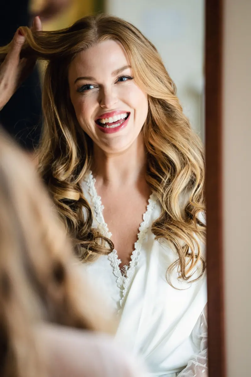 Sara smiling into the mirror as her hair is finished