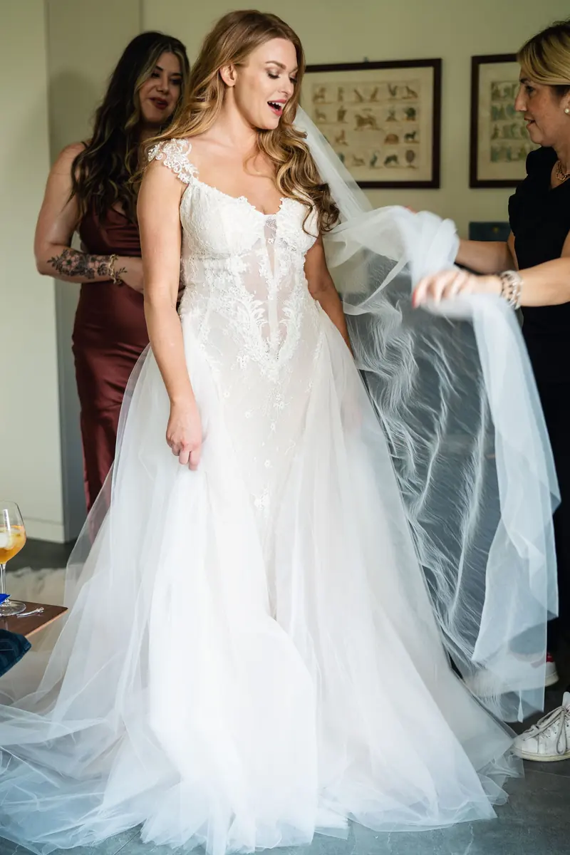 Sara in her gown as her friends arrange the long veil