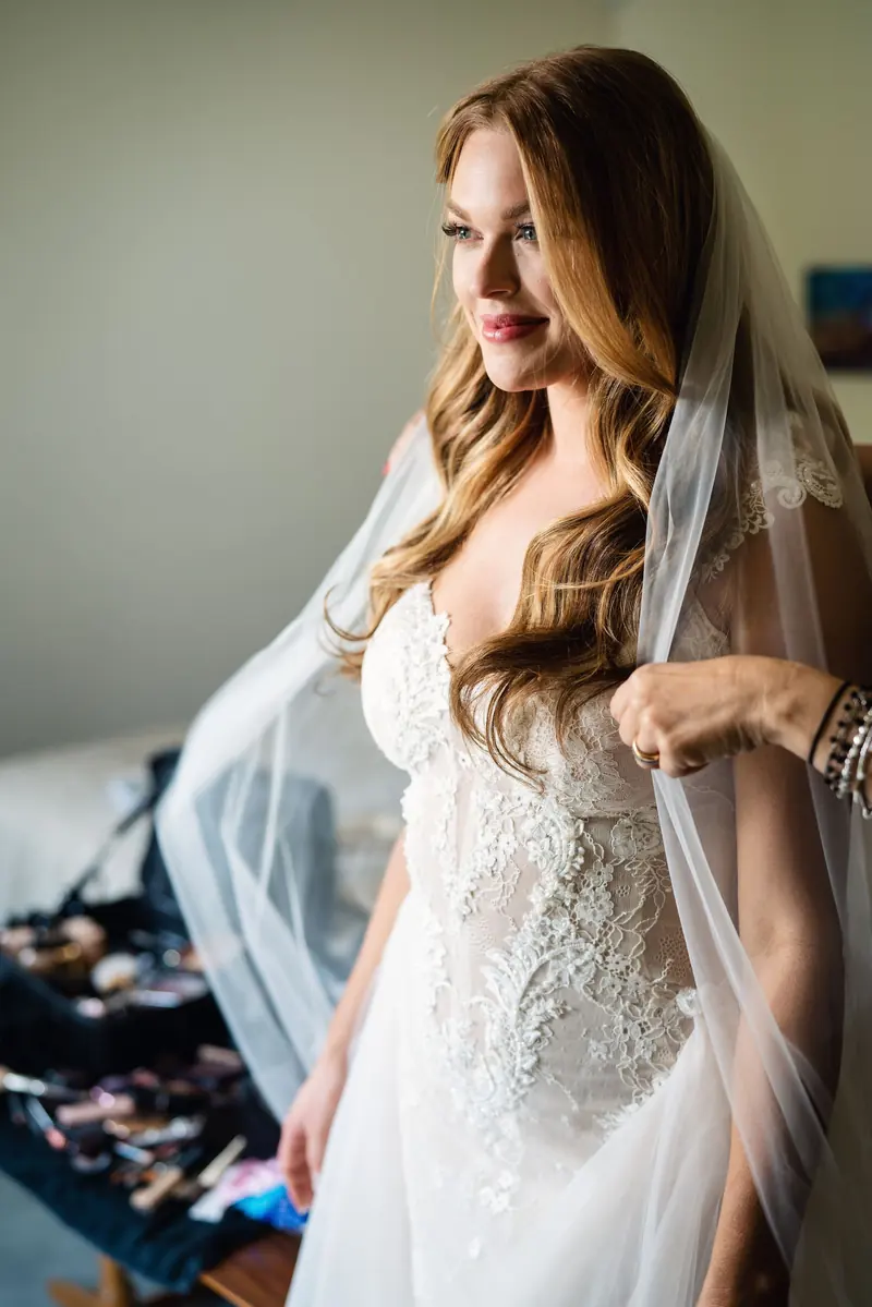 Sara looking down as her veil is pinned in place