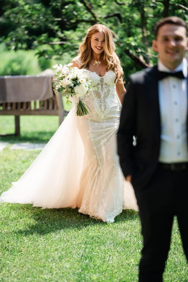 Sara walking up behind Drew on the lawn for the first look