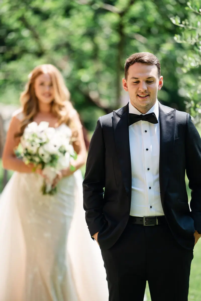 Bride and groom standing together on the lawn after their first look
