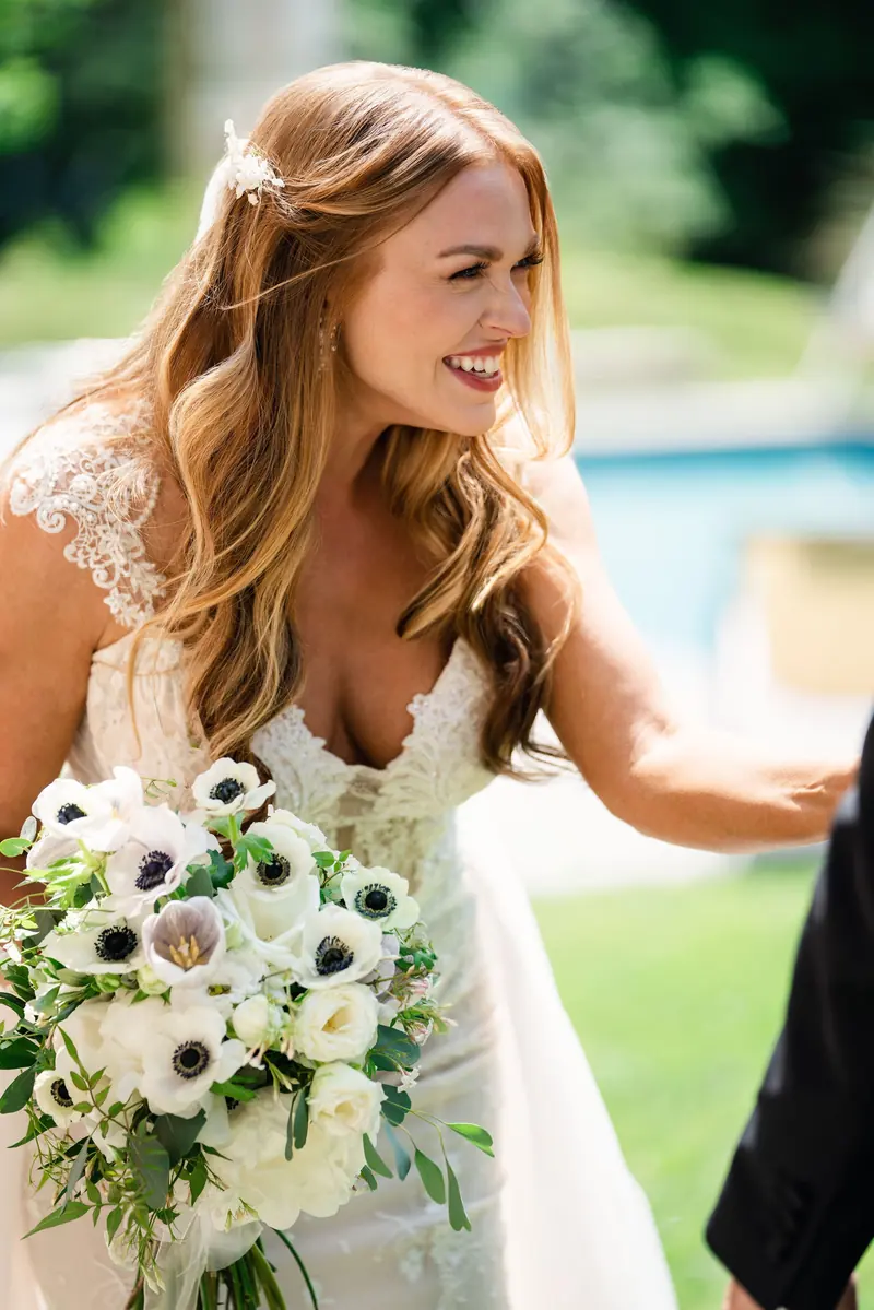 Bride laughing with her bouquet of white flowers