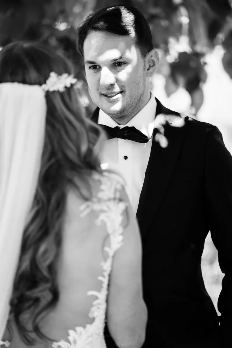 Black and white photo of the groom smiling over the bride's shoulder