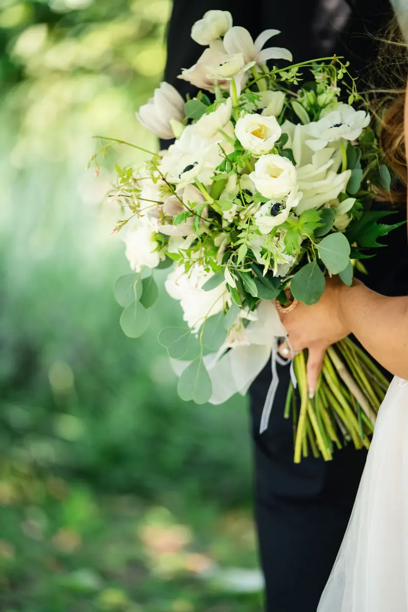 Bouquet of white roses and anemones in the bride's hands