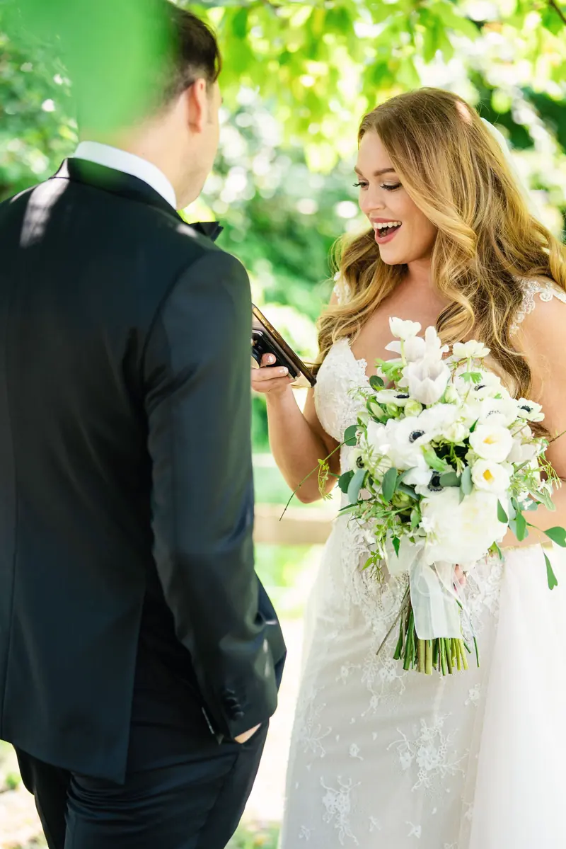 Bride with her bouquet facing the groom under the trees