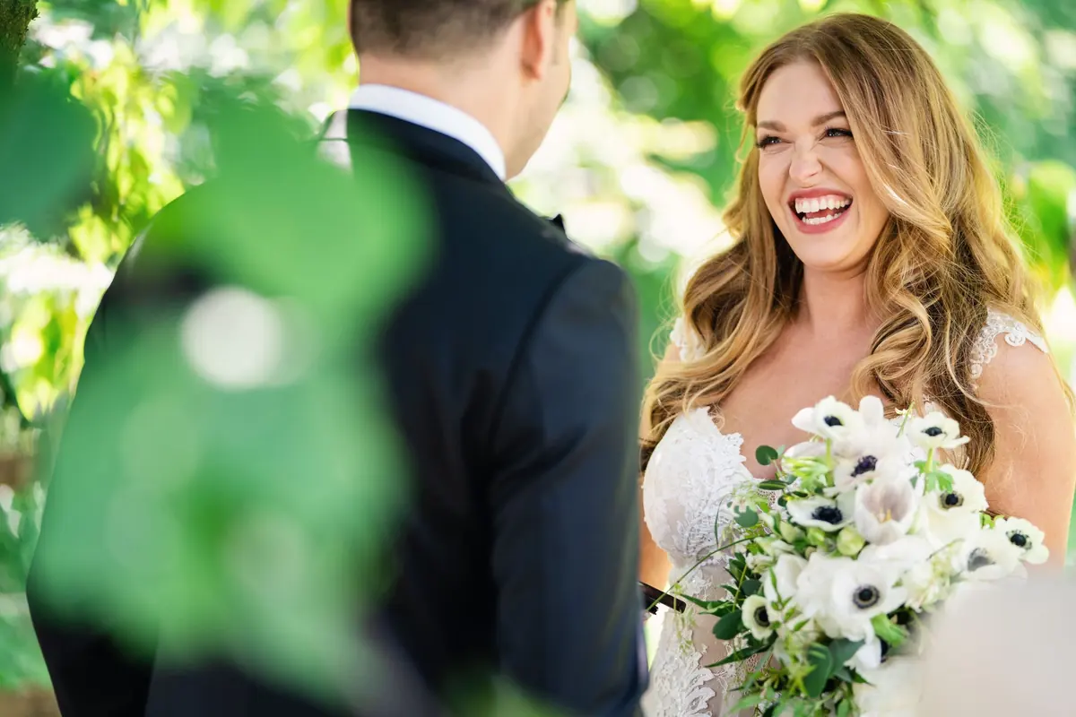 Sara laughing with her bouquet, seen past Drew's shoulder