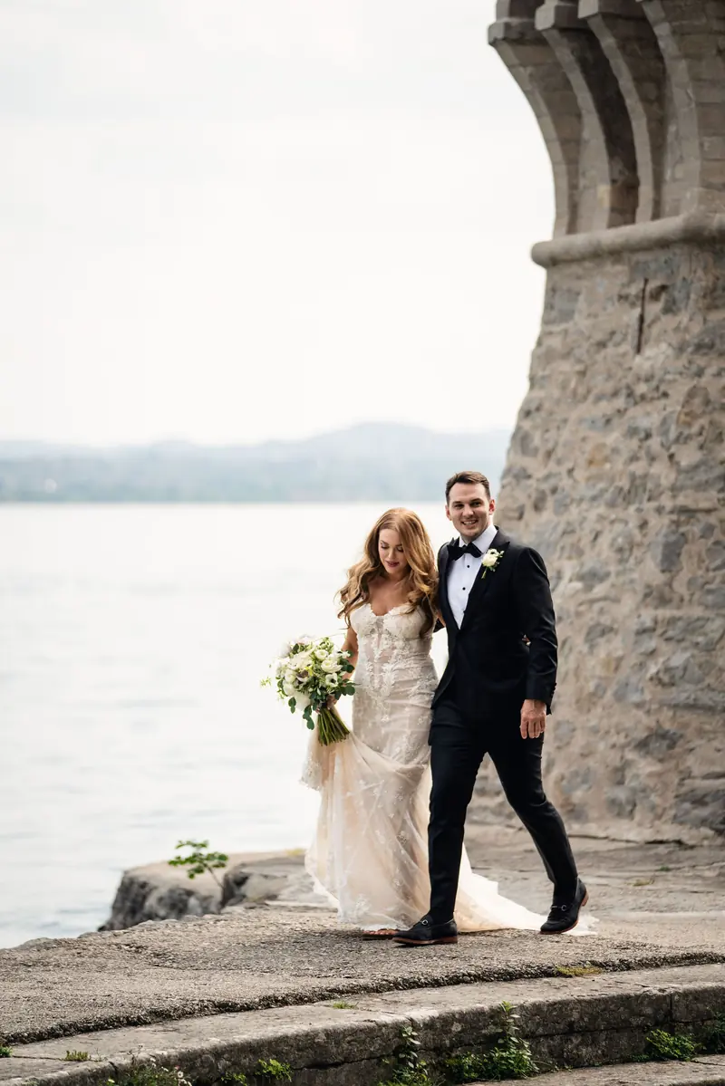Bride and groom by the stone tower on the shore of Lake Garda