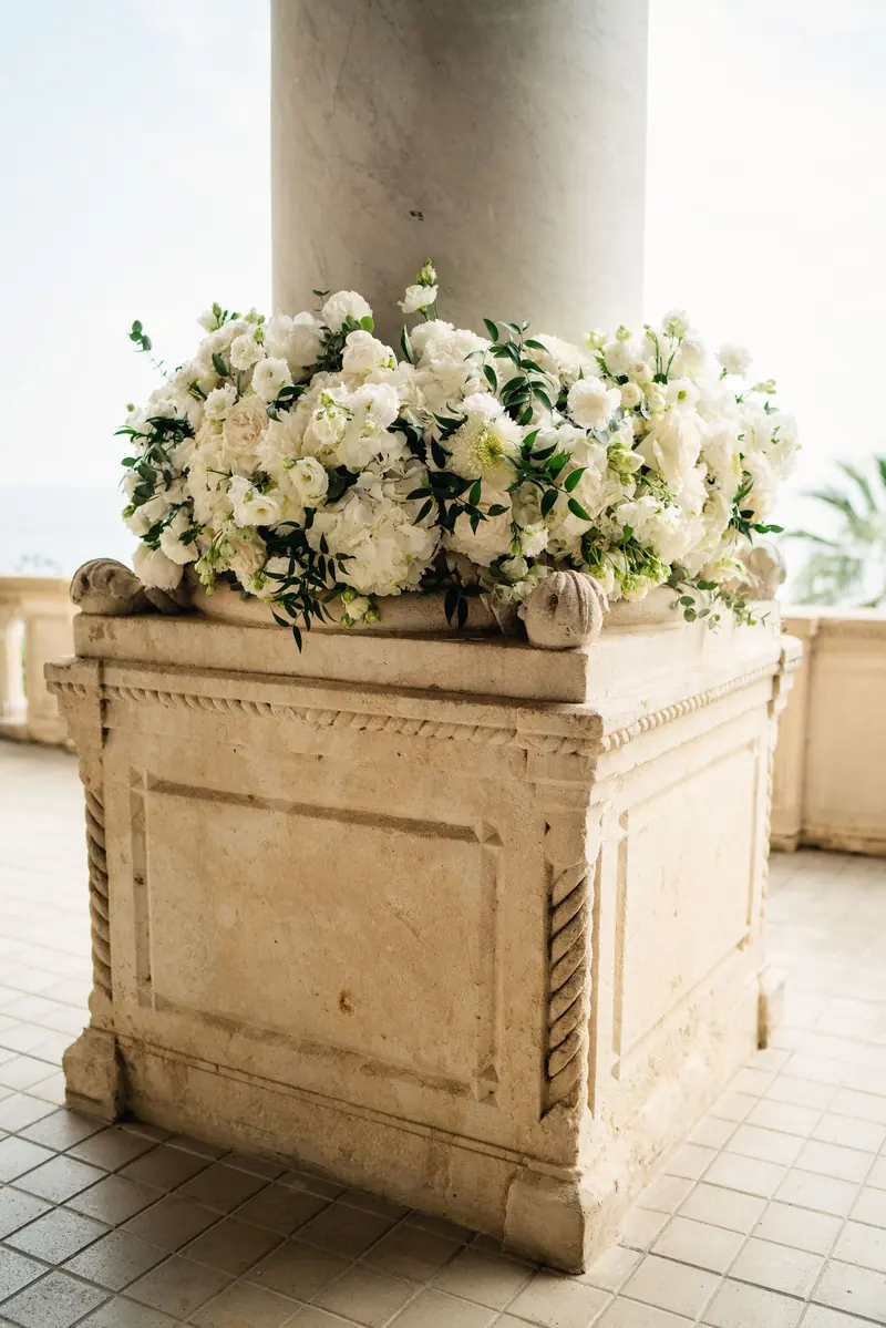 Stone urn of white roses and hydrangeas beside a loggia column