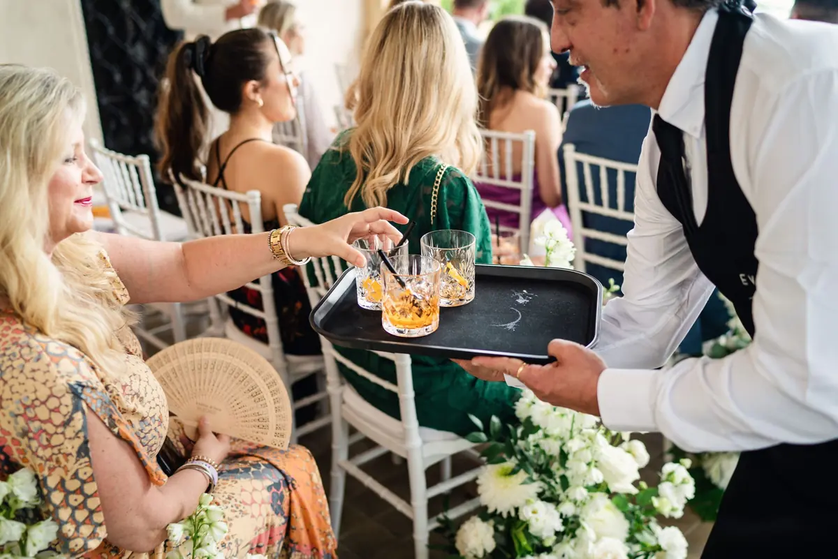 A waiter serving drinks to seated guests before the ceremony