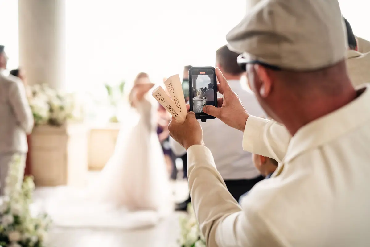 A guest filming on his phone as Sara walks in