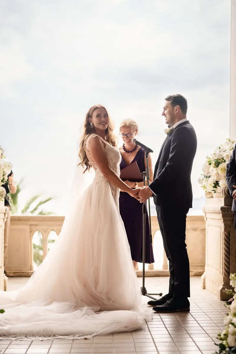 Bride and groom facing each other at the ceremony with the lake behind