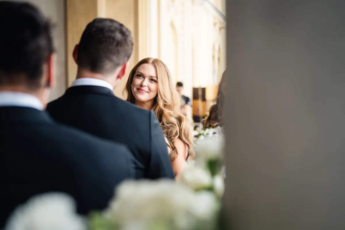 Sara seen between the groomsmen's shoulders at the ceremony