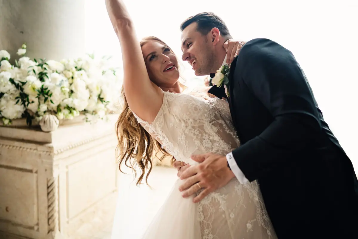 Sara throwing an arm in the air as Drew hugs her after the vows