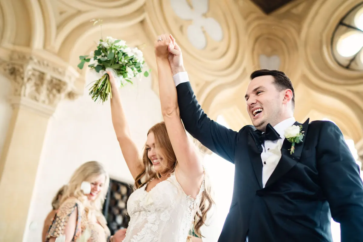 Sara and Drew cheering, her bouquet raised high