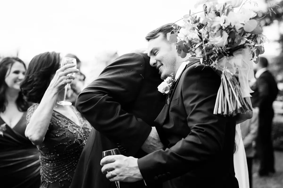 Guests hugging Sara and Drew after the ceremony, in black and white