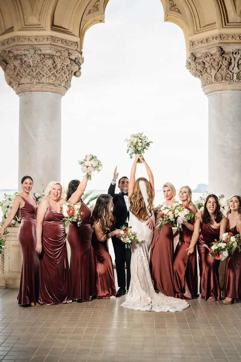 Sara and her bridesmaids cheering under the loggia arches