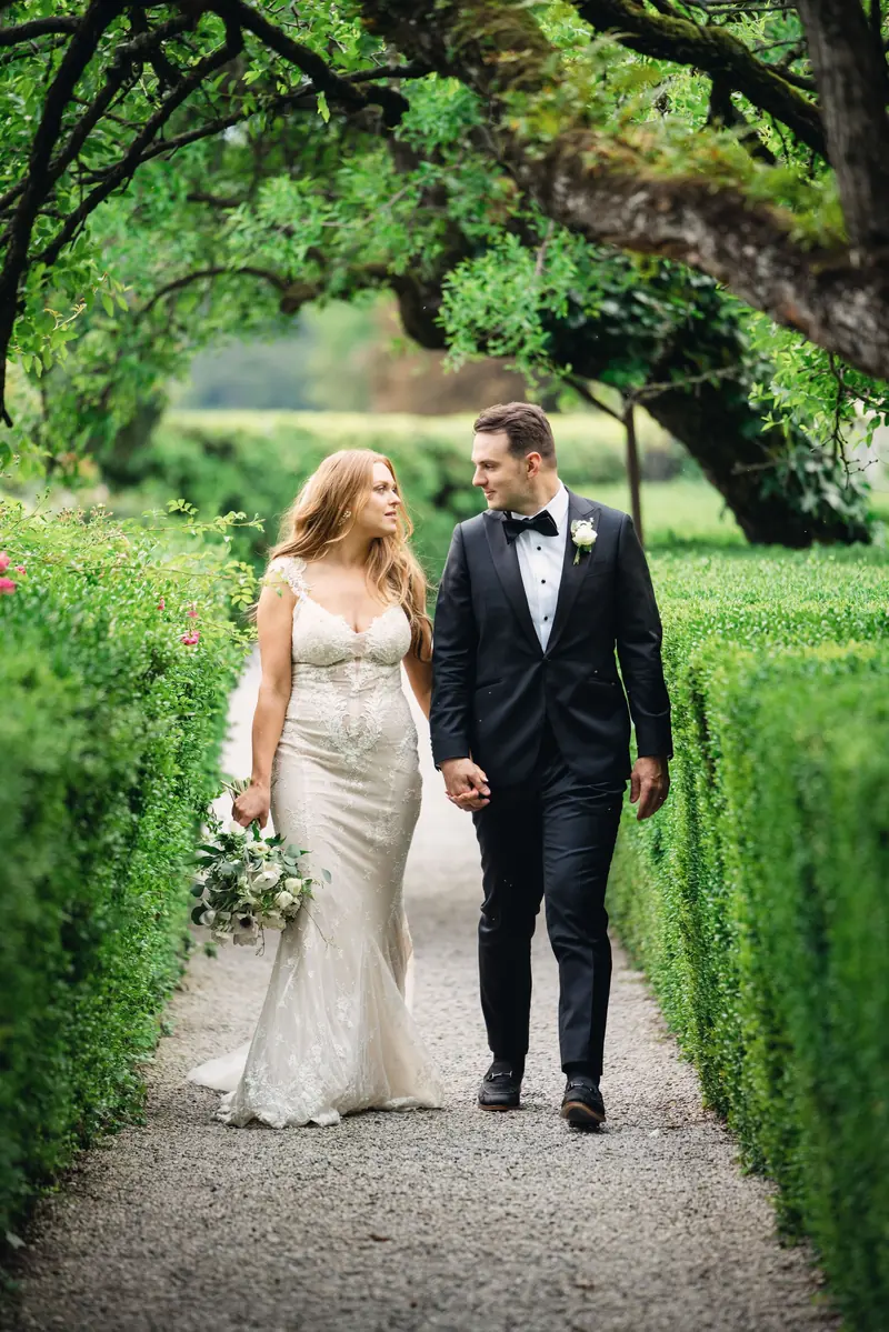 Bride and groom walking between clipped hedges in the Italian garden