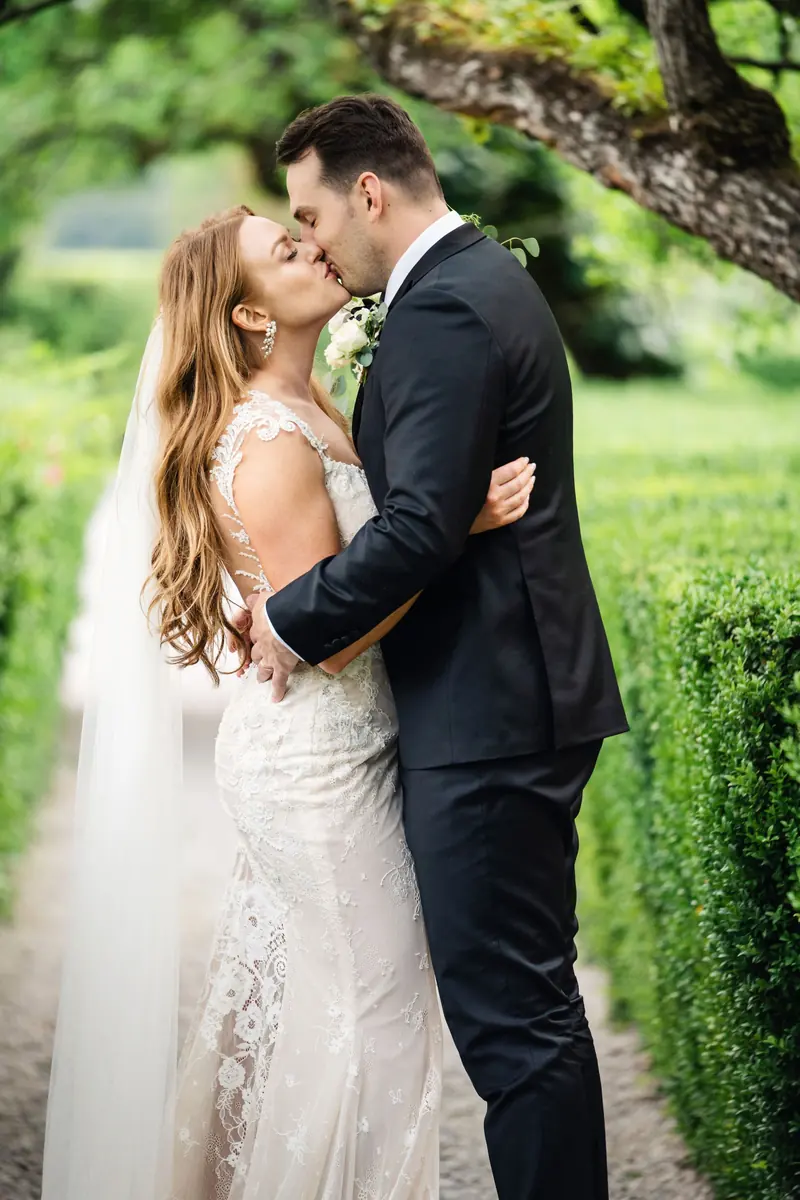 Groom kissing the bride's forehead in the gardens