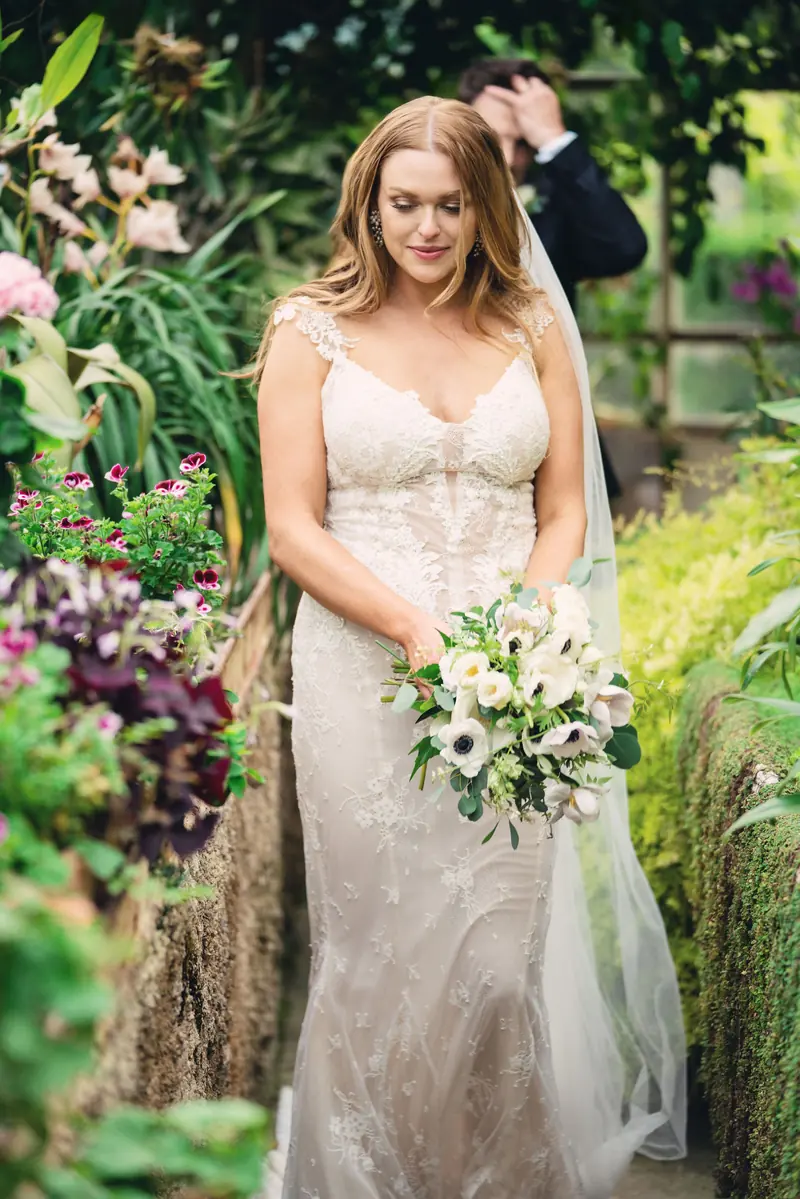 Bride with her bouquet among flowering plants in the gardens