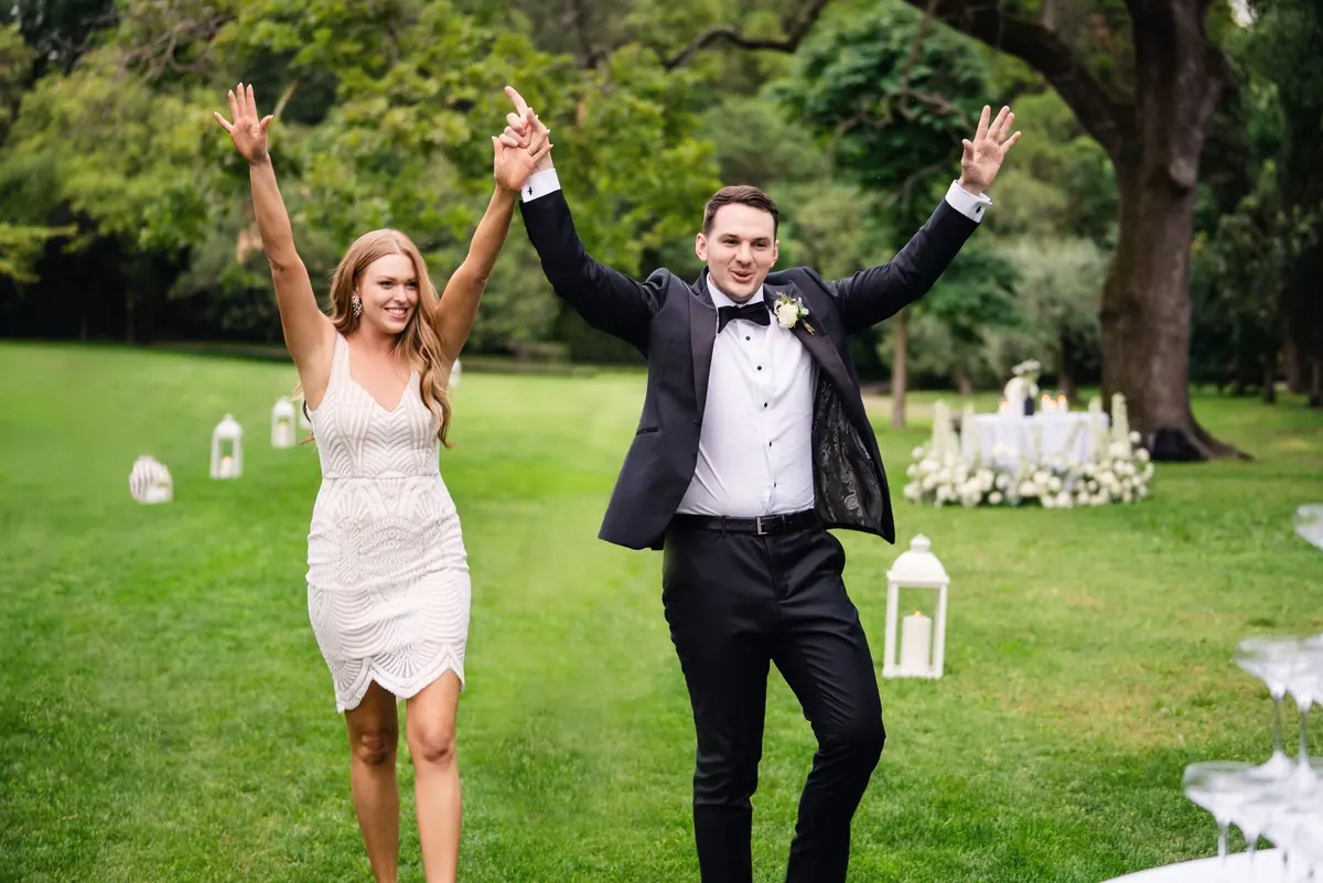 Sara and Drew arriving at the reception with their arms in the air