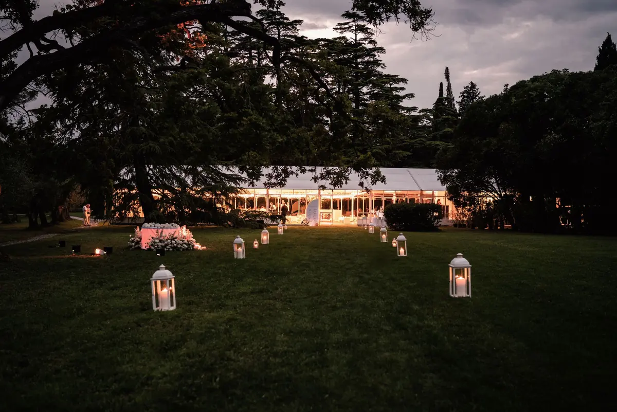 The marquee glowing at dusk with lanterns on the lawn