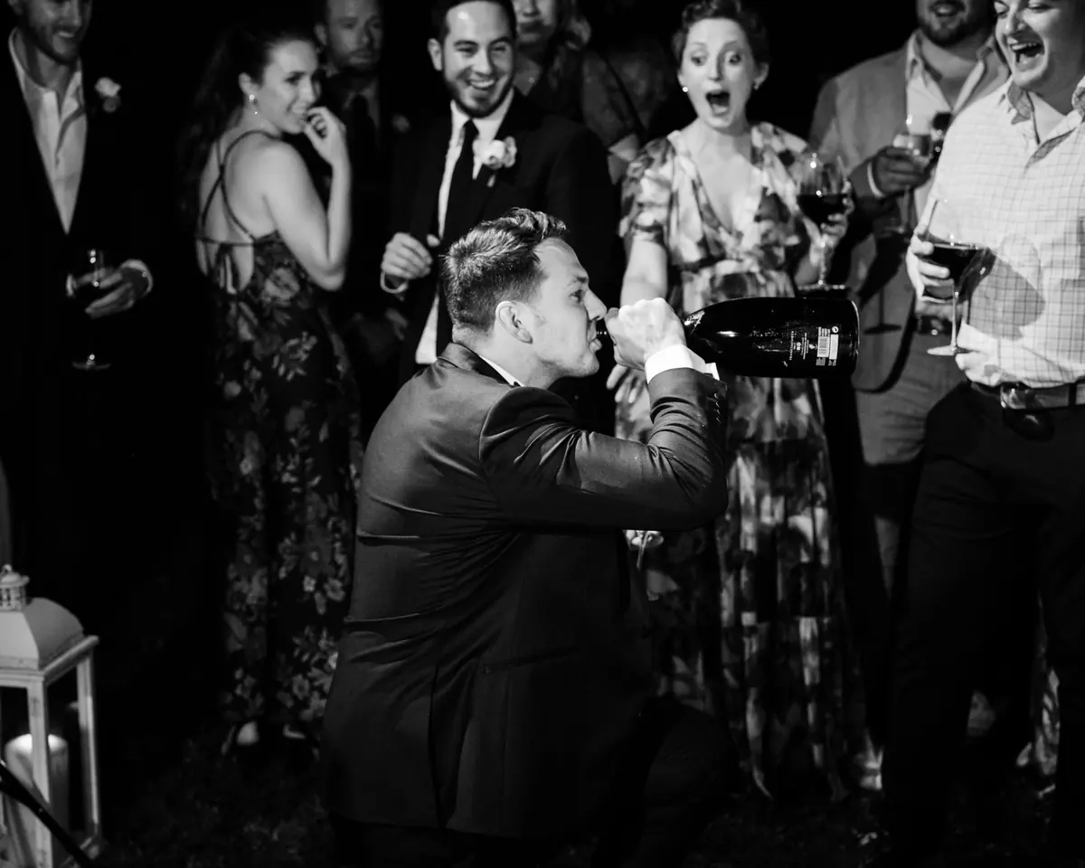 Guests cheering around Drew at the party, in black and white